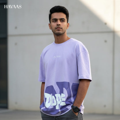 Man wearing a light purple t-shirt with a logo, standing outdoors.